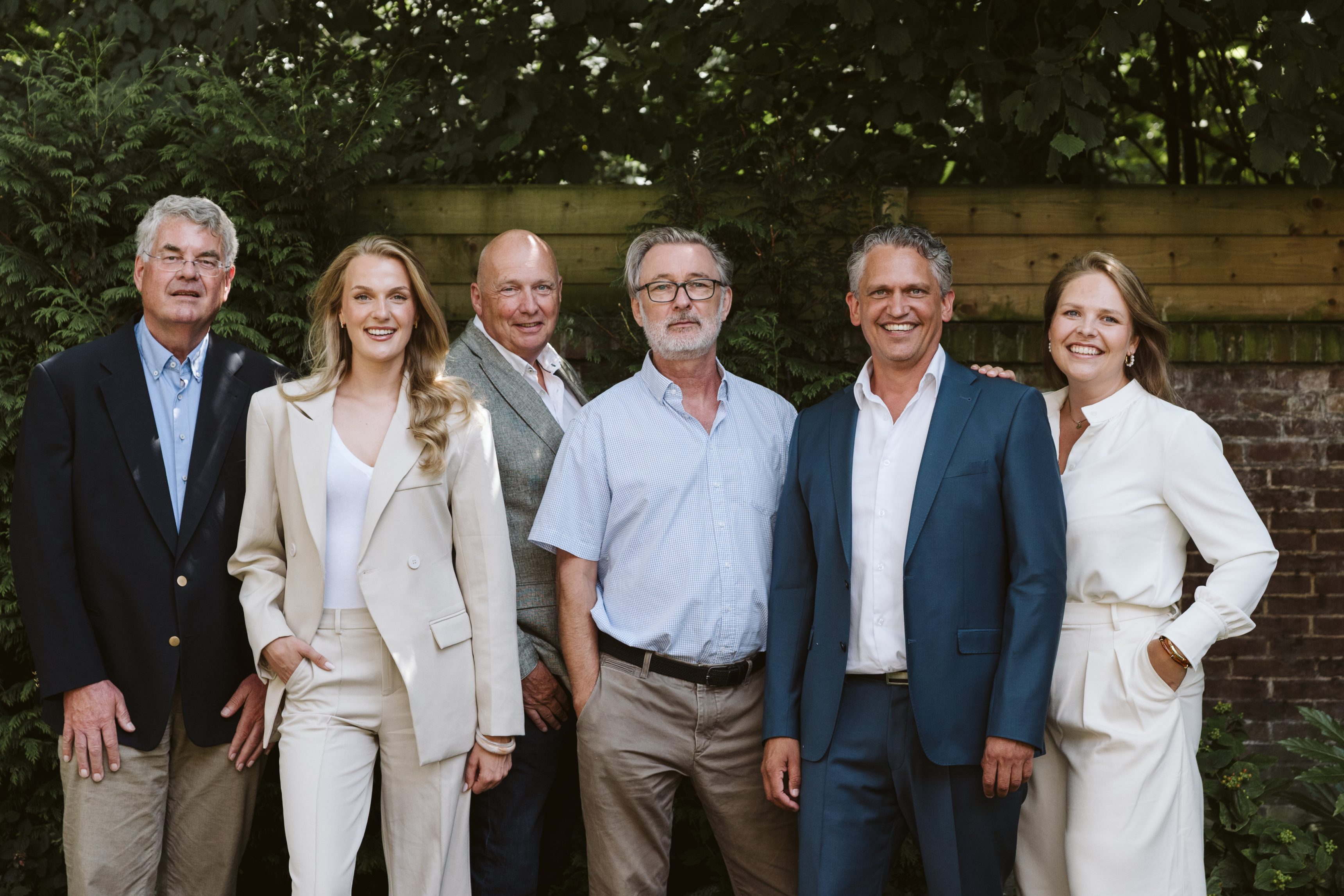 Het team van Oosterhof Makelaars in de tuin bij het kantoor