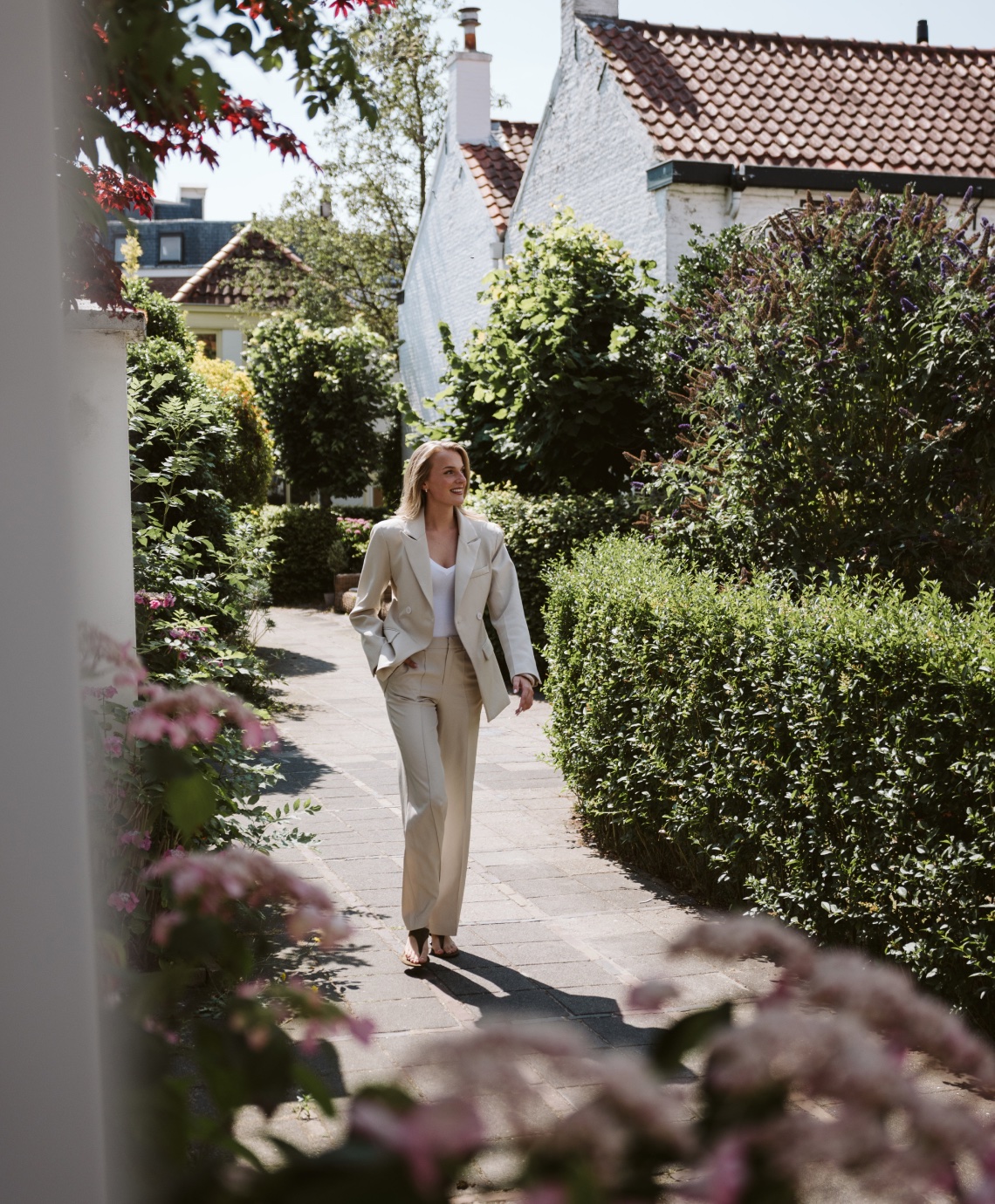 Makelaar loopt door een tuinpad langs een woning